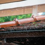 Close-up of rain hitting a tile roof and gutter system