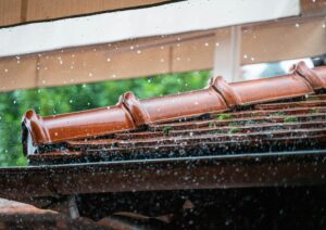 Close-up of rain hitting a tile roof and gutter system