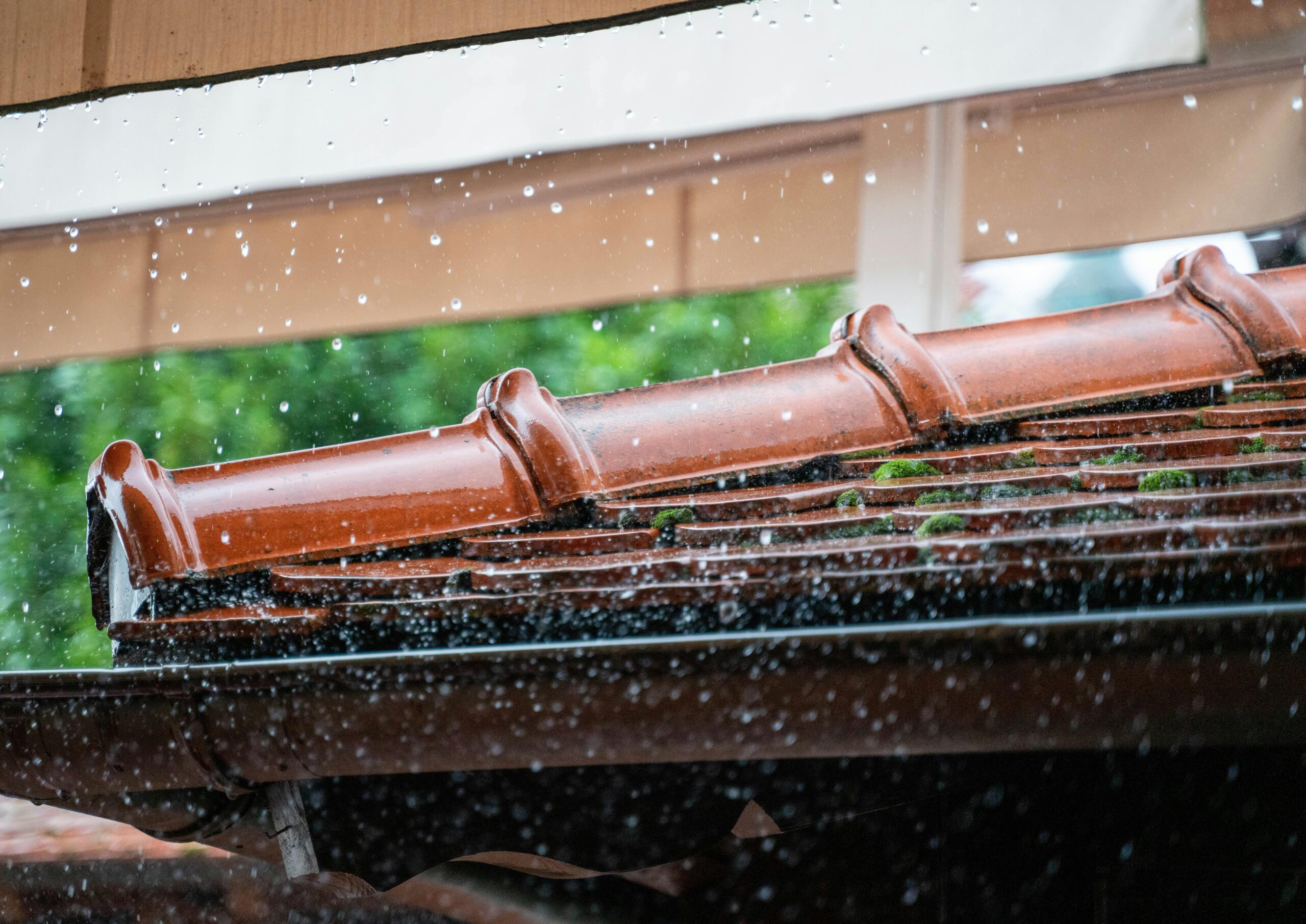 Close-up of rain hitting a tile roof and gutter system