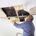 Property owner inspecting interior ceiling damage from a roof leak.